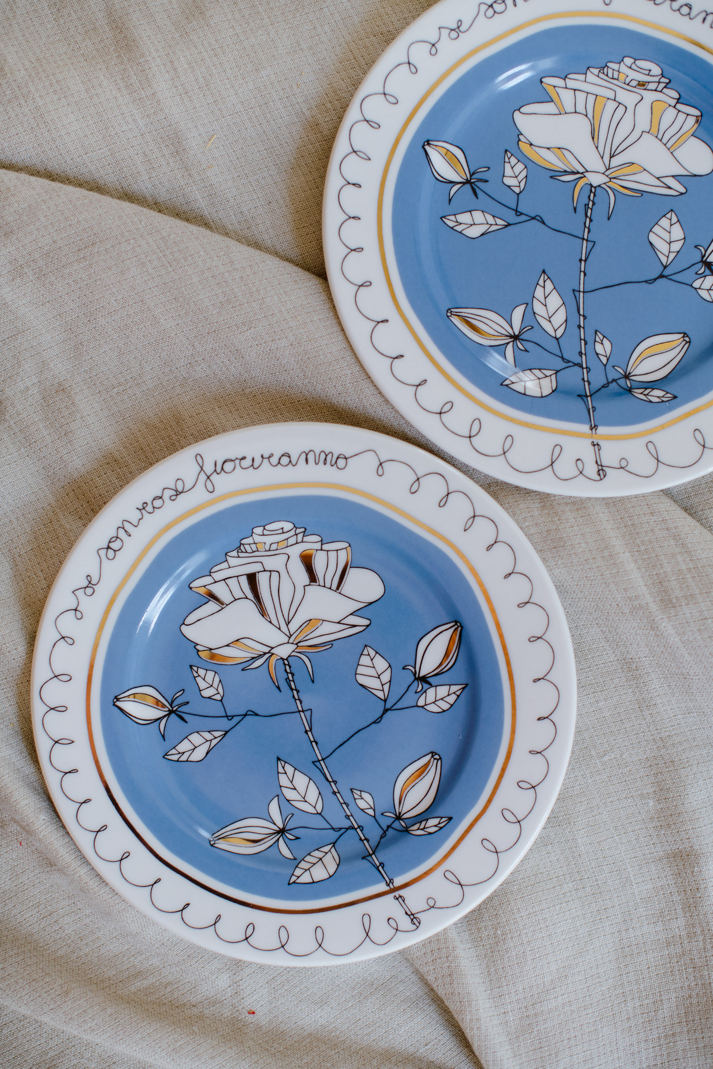 piatto in porcellana azzurro decorato con dettagli oro, disegno di una rosa nei colori bianco e azzurro polvere